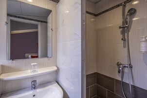 Un baño con lavamanos blanco, espejo y ducha.