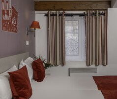 Una habitación de hotel con cama, almohadas, lámpara, cortinas y radiador.