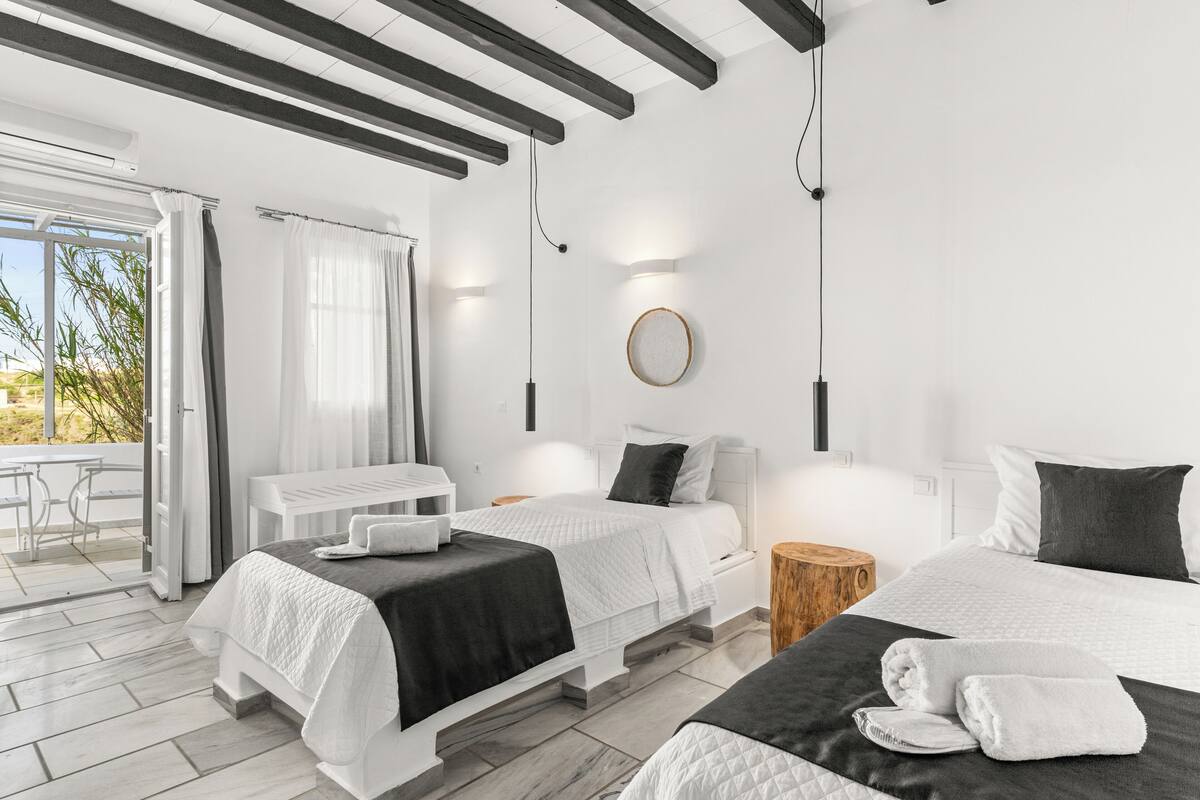 Una habitación de hotel moderna con dos camas, un comedor y vistas al exterior.