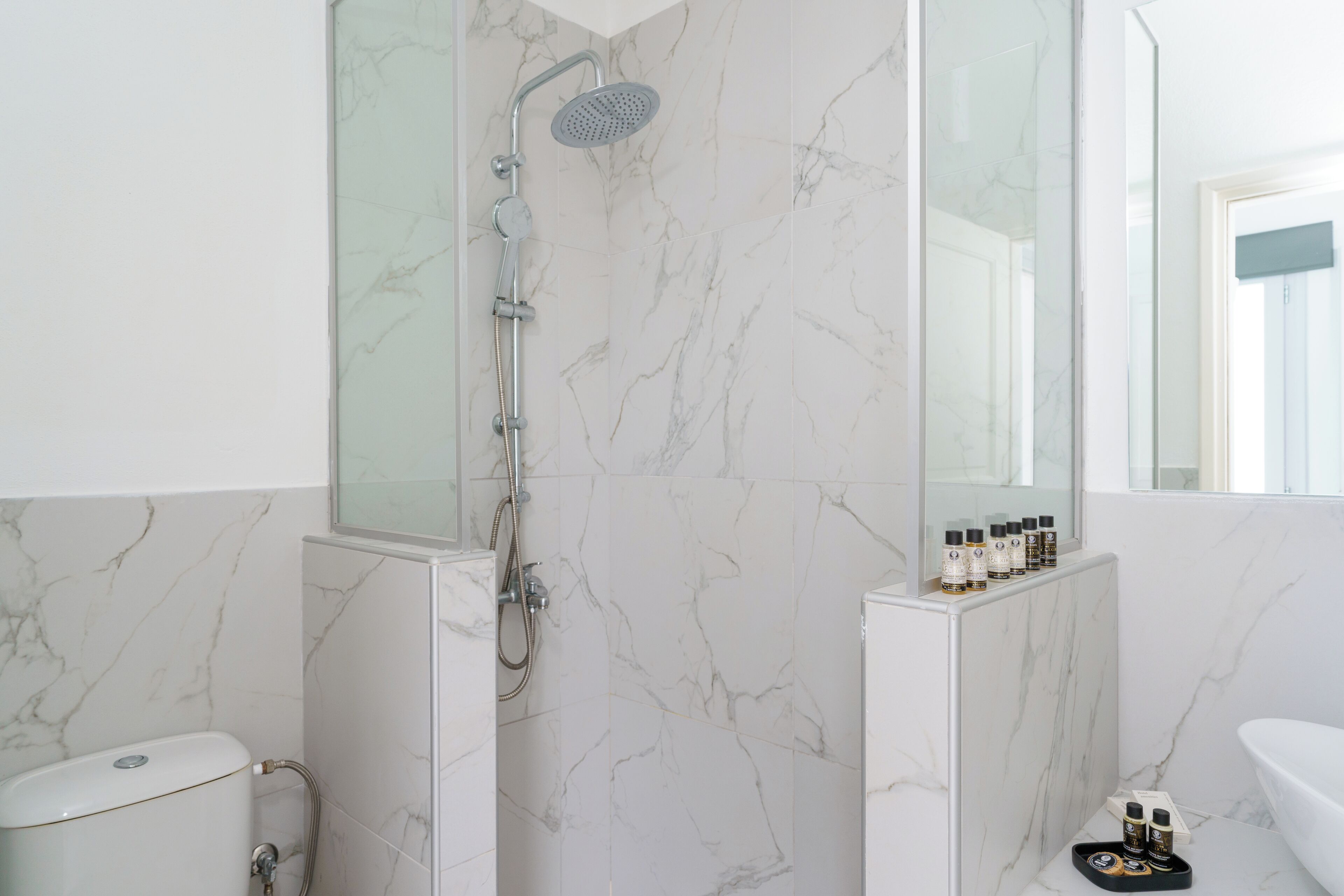 Un baño moderno con ducha, inodoro y tocador con artículos de aseo.