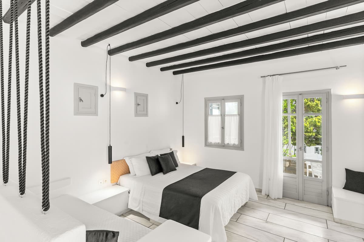 Un dormitorio moderno con una cama grande, mesitas de noche, una lámpara colgante y vistas a través de un ventanal.