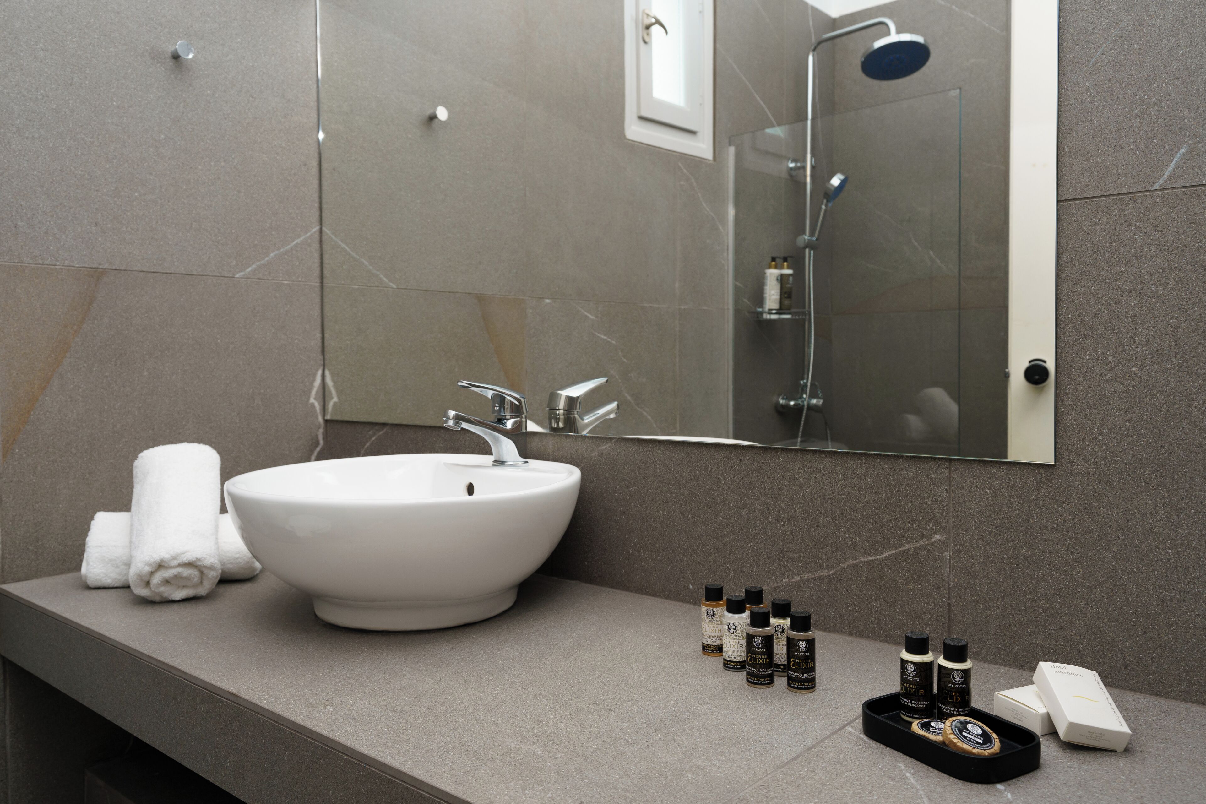 Un baño moderno con un lavabo blanco, un espejo grande y una ducha.