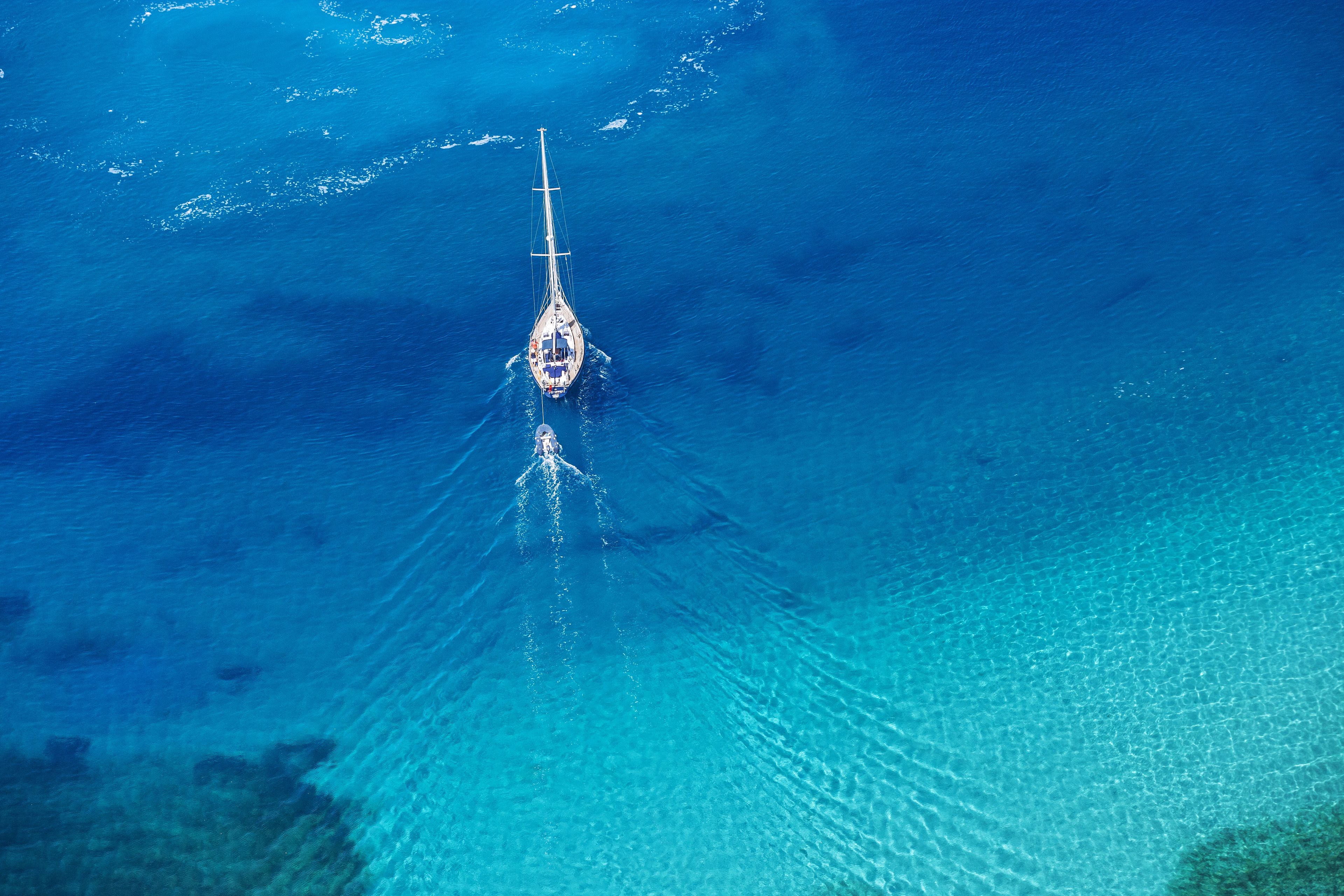 Vista aérea de um veleiro em águas azul-claras.