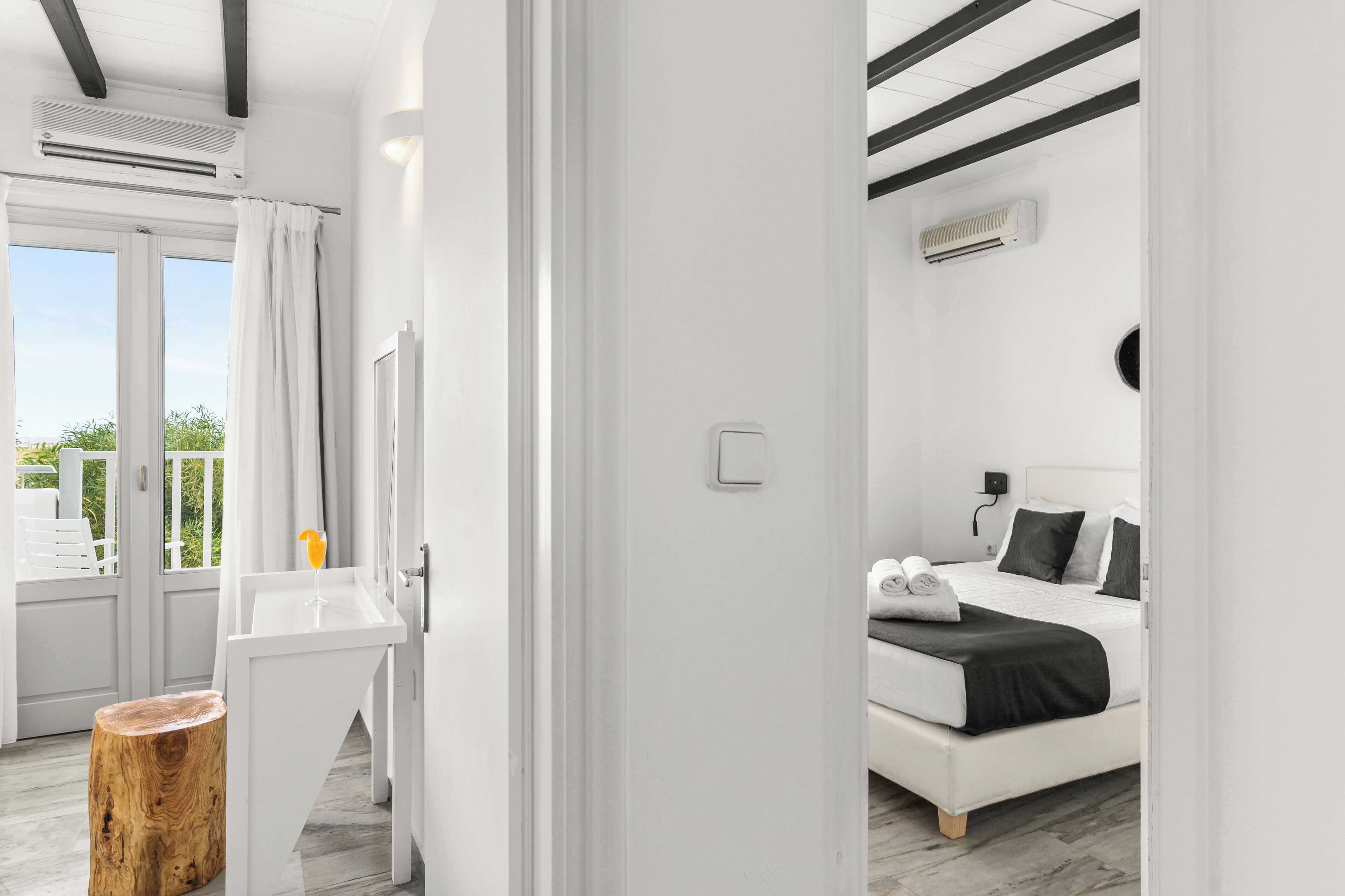 A modern bedroom with a bed, bedside table, and a view of the outdoors.
