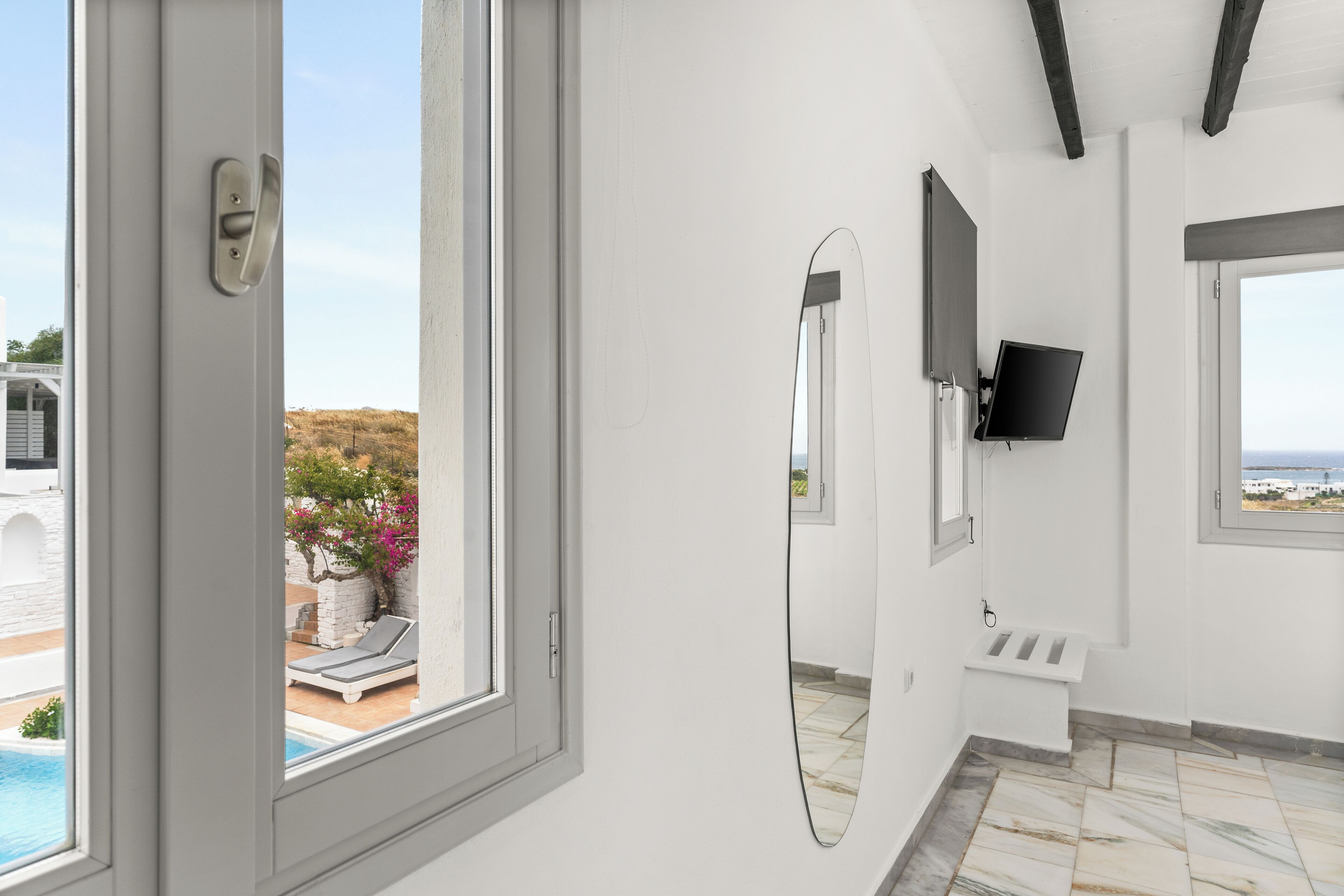 Een moderne badkamer met een groot raam, een spiegel, een wastafel en een televisie.