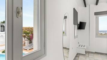 Een moderne badkamer met een groot raam, een spiegel, een wastafel en een televisie.
