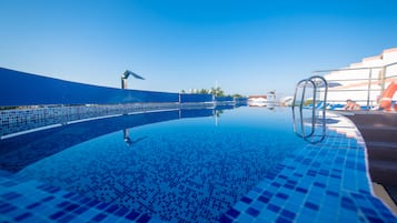 Una piscina techada, sombrillas, sillones reclinables de piscina