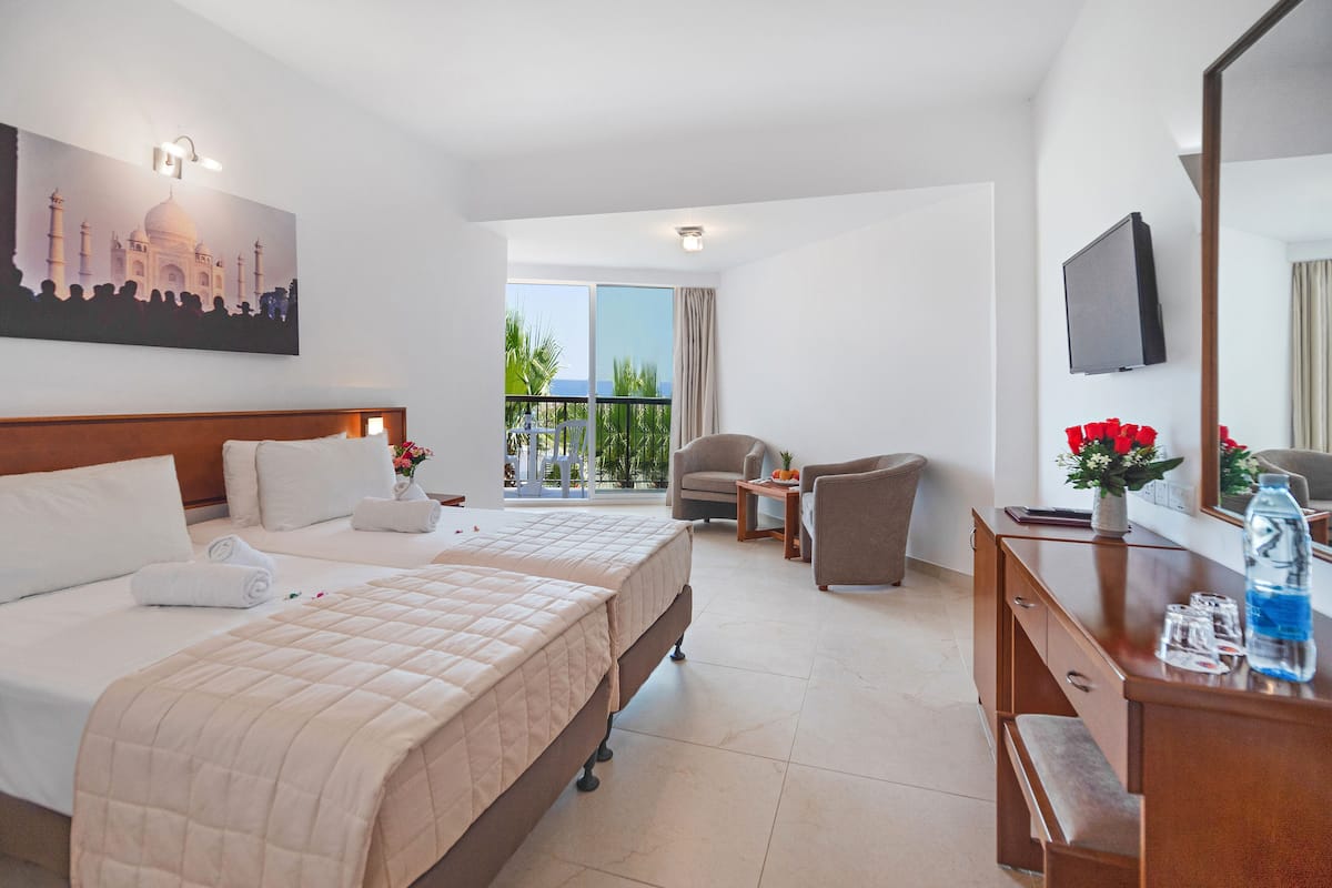 A hotel room with a bed, a desk, a chair, a balcony with a view, and a TV.