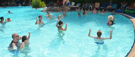 Une piscine où des personnes se baignent et profitent de l’eau, entourée de chaises longues et de parasols.