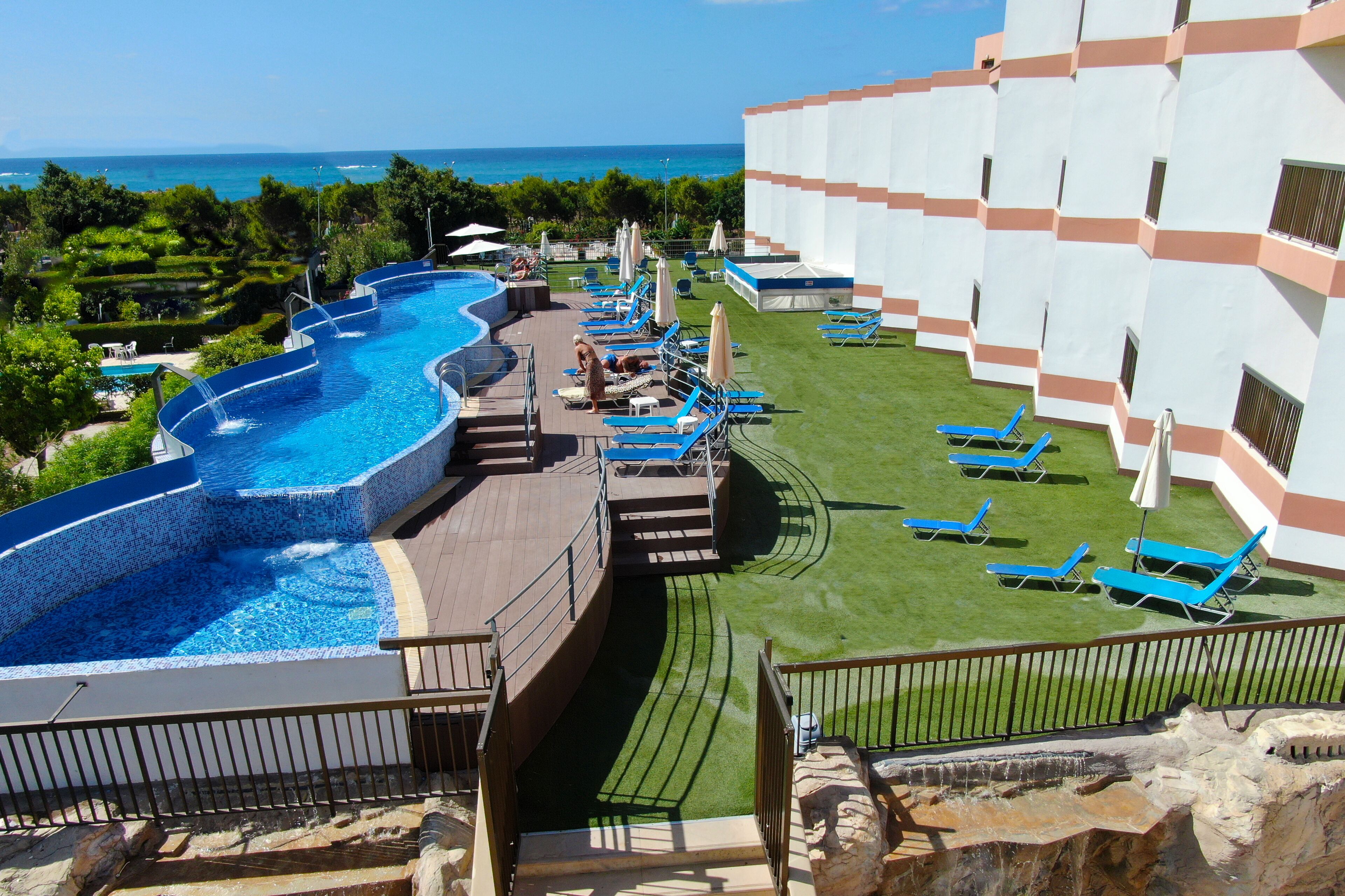 Um resort com uma grande piscina infinita, espreguiçadeiras e vista para o oceano.