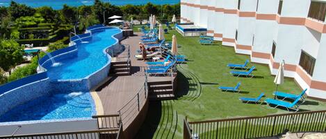 Um resort com uma grande piscina infinita, espreguiçadeiras e vista para o oceano.