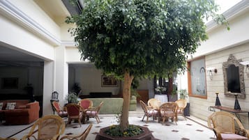 Un hall espacioso con un gran árbol, asientos cómodos y suelo de baldosas.