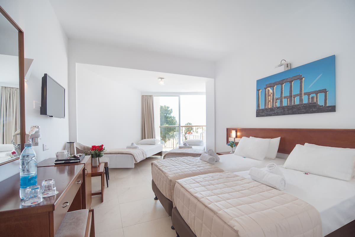 A hotel room with two beds, a desk, a chair, a TV, and a balcony with a view.