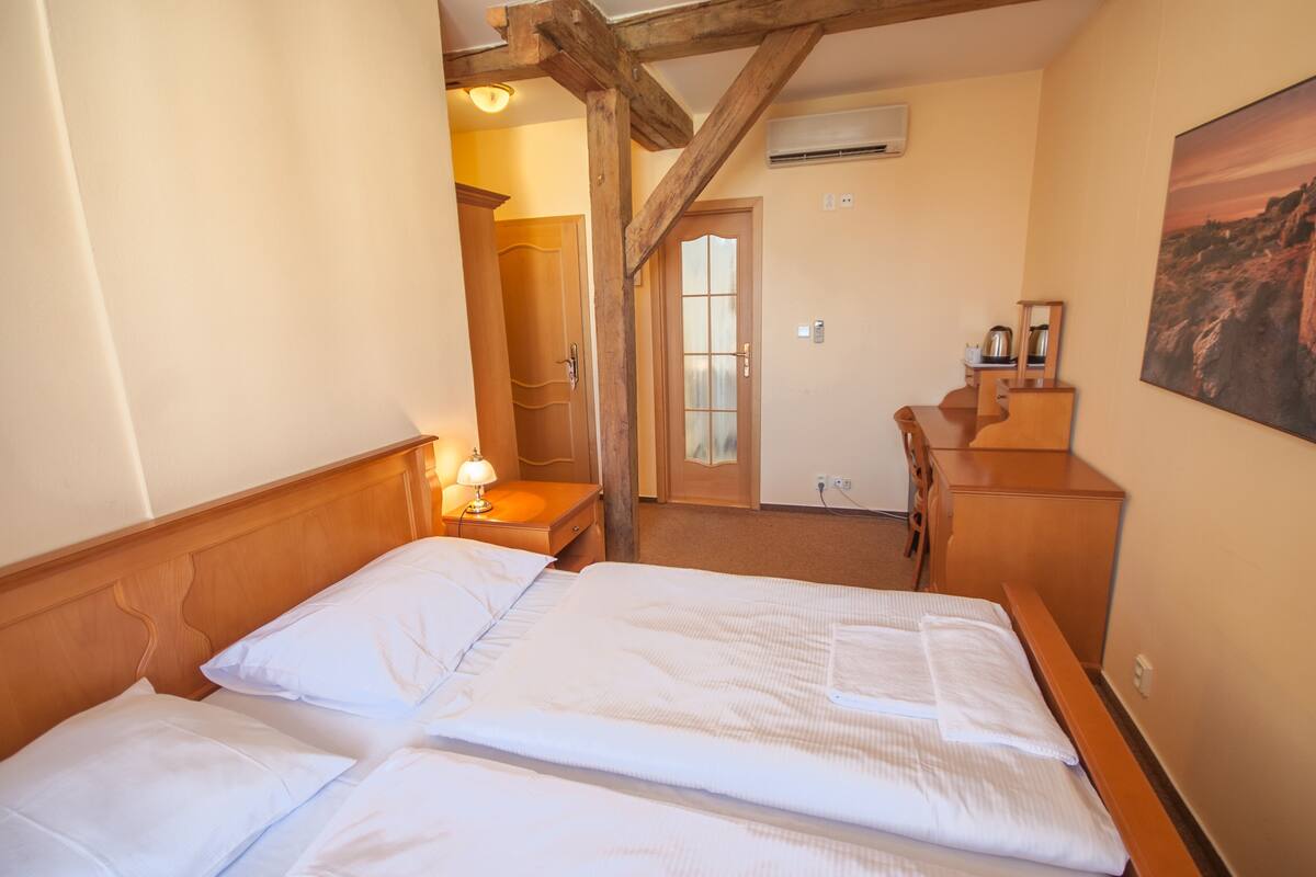 Ein Hotelzimmer mit zwei Betten, Holz-Kopfteilen, einer Holzkommode, einem Nachttisch mit Lampe und einem Bild an der Wand.