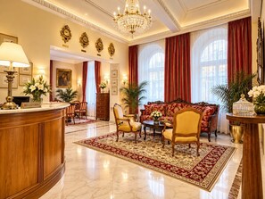 A luxurious lobby with a reception desk, a sofa set, and a chandelier. - Hotel St George - Czech Leading Hotels (Prague)