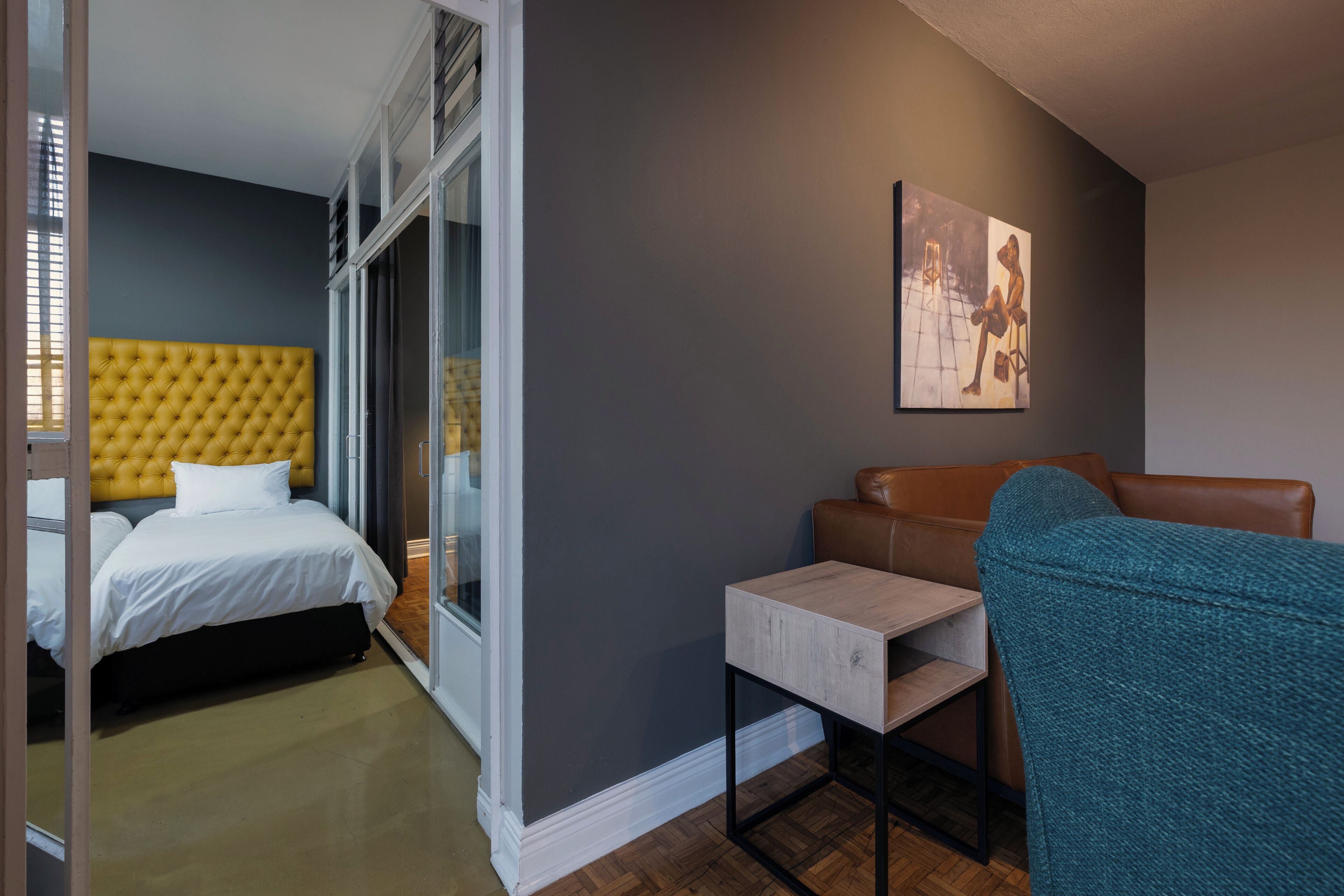 Una habitación de hotel con una cama, zona de estar y un cuadro en la pared.