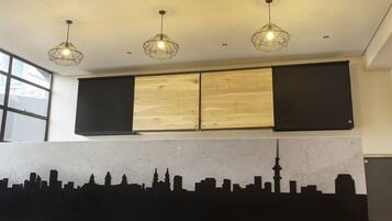 A modern interior with a city skyline mural, black sliding doors, and three pendant lights.