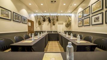 A conference room with a long table, chairs, water bottles, and framed animal headpieces on the wall.