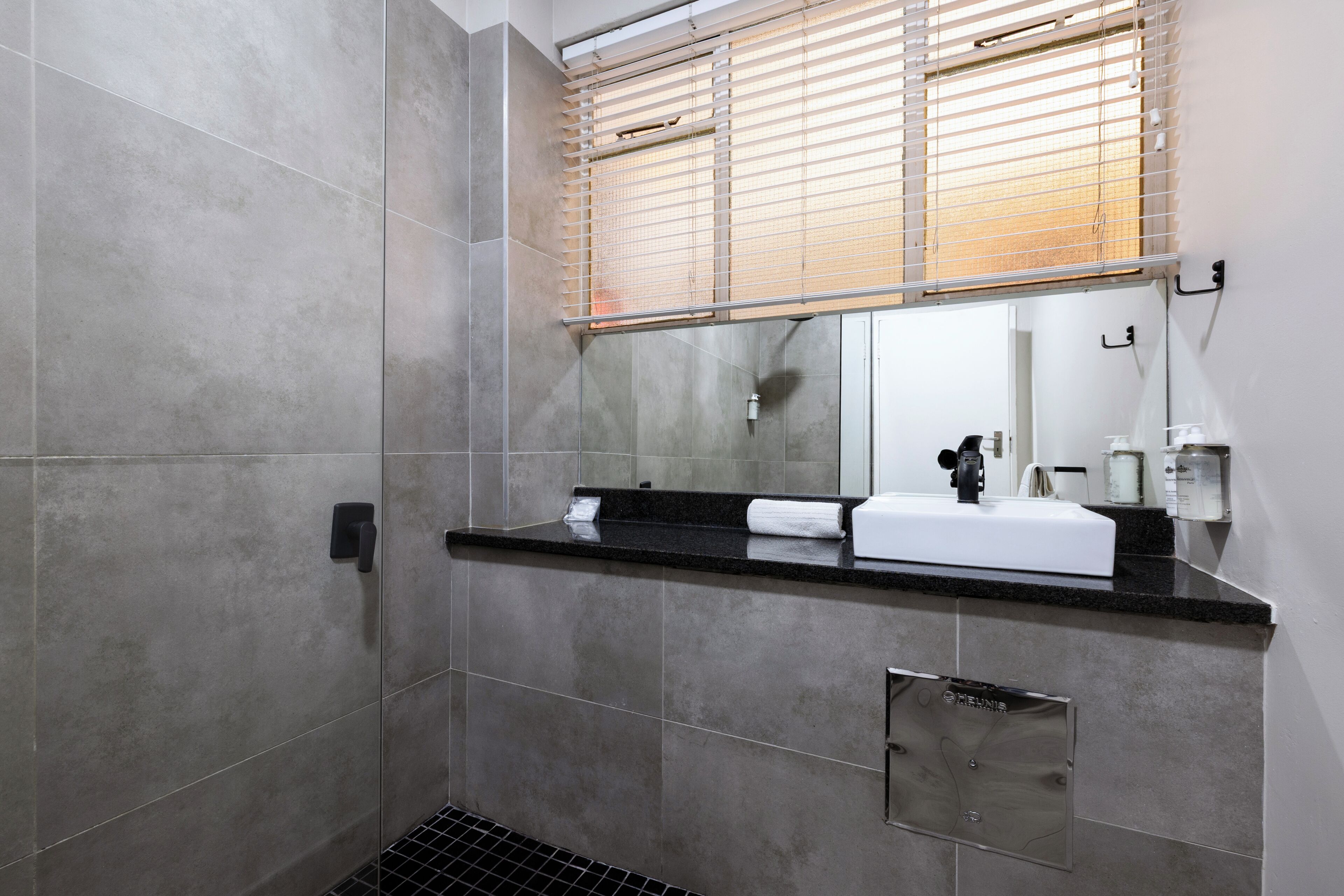 Een moderne badkamer met een douche, wastafel en spiegel.