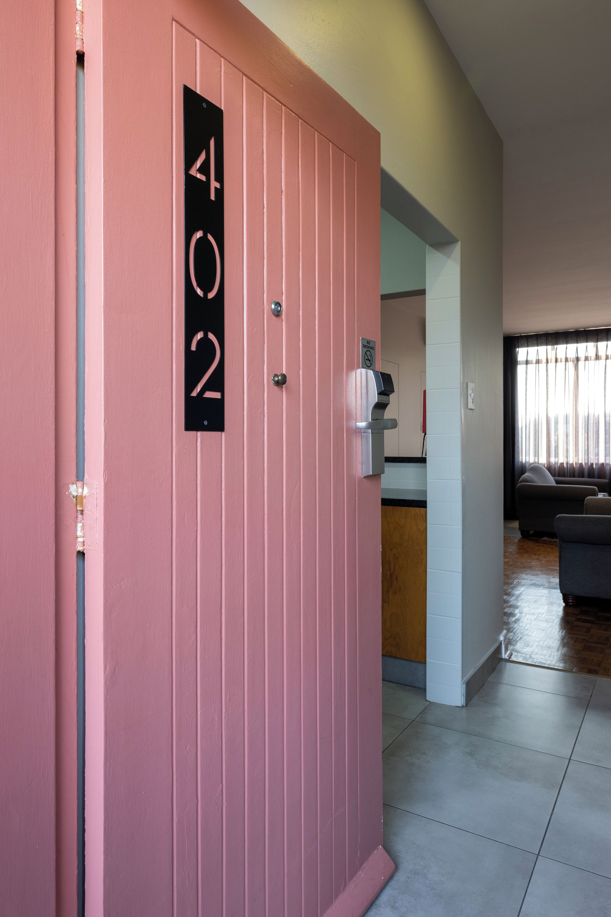 A pink door with a black number plate reading '402'.