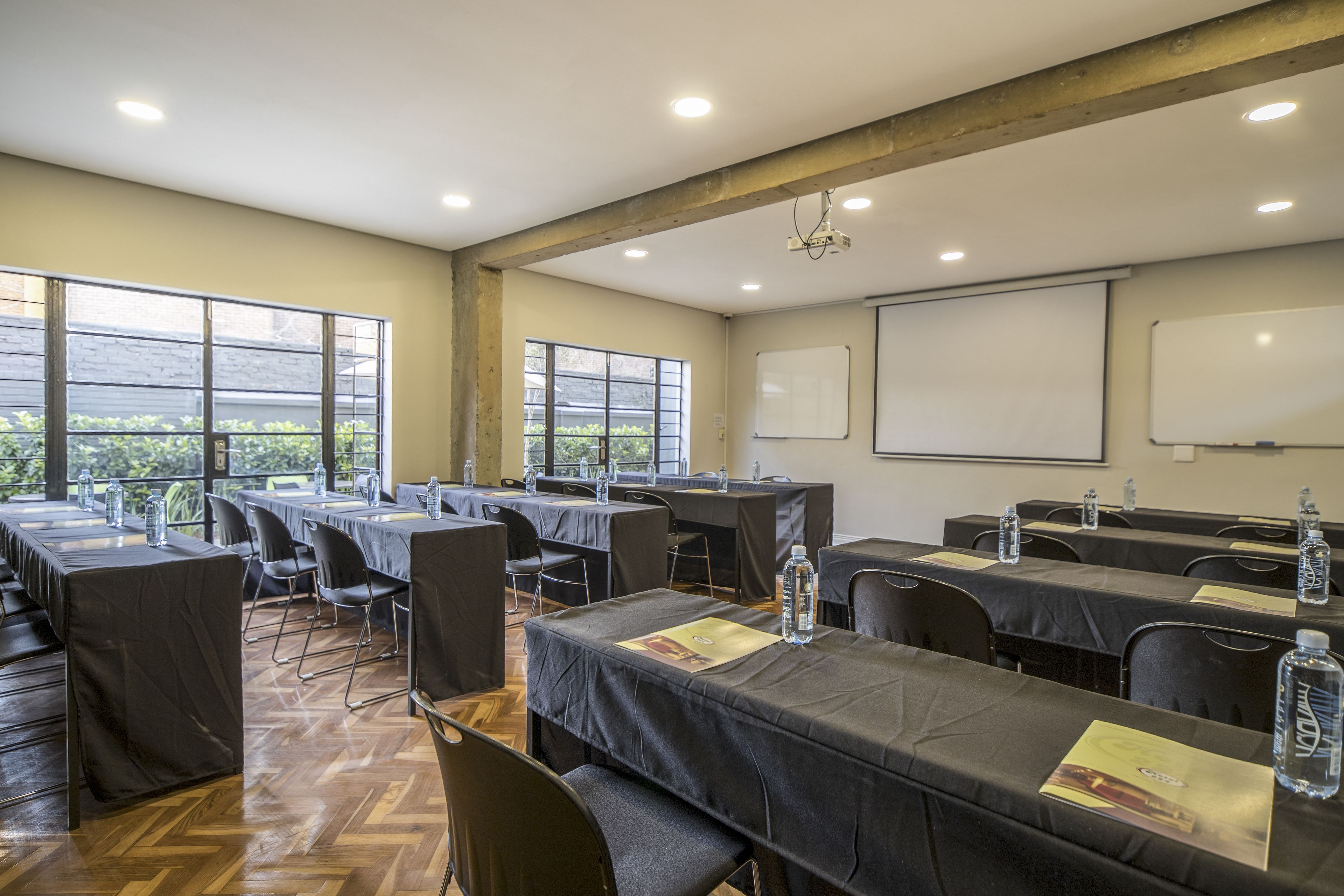 Un salón de conferencias con mesas, sillas, un proyector y una pizarra.