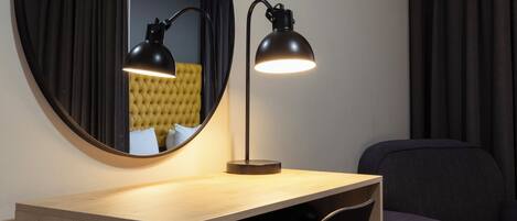 Una habitación moderna con un espejo redondo, un escritorio con una silla y un sofá.