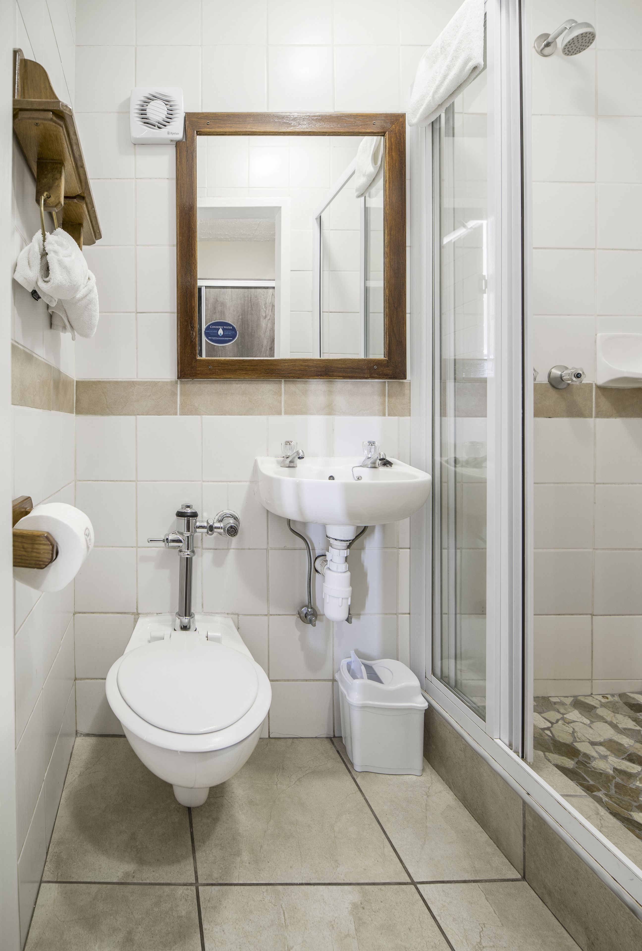 A bathroom with a toilet, sink, mirror, shower, and a towel rack.