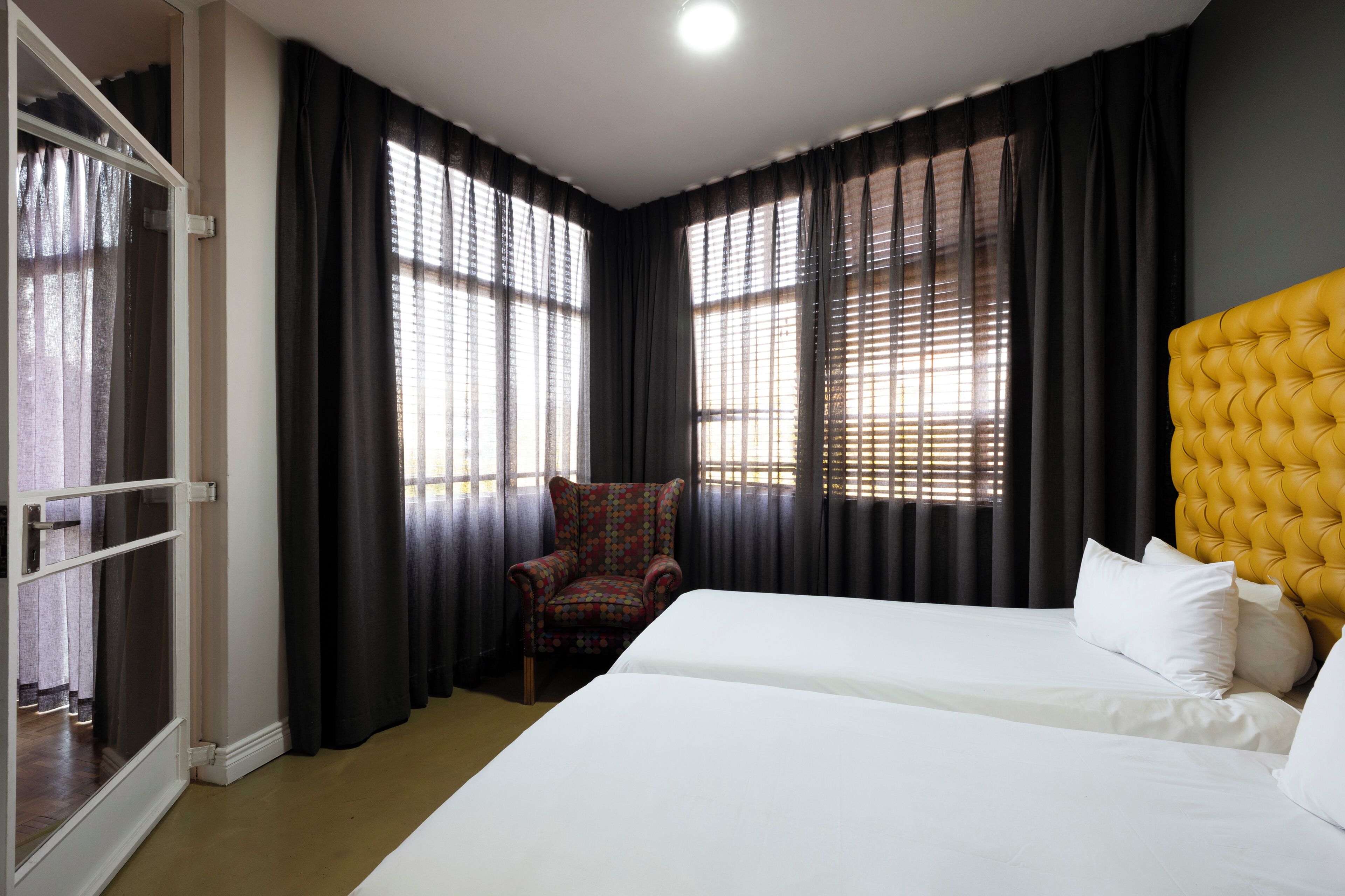 A hotel room with a bed, a chair, and a window with blinds.