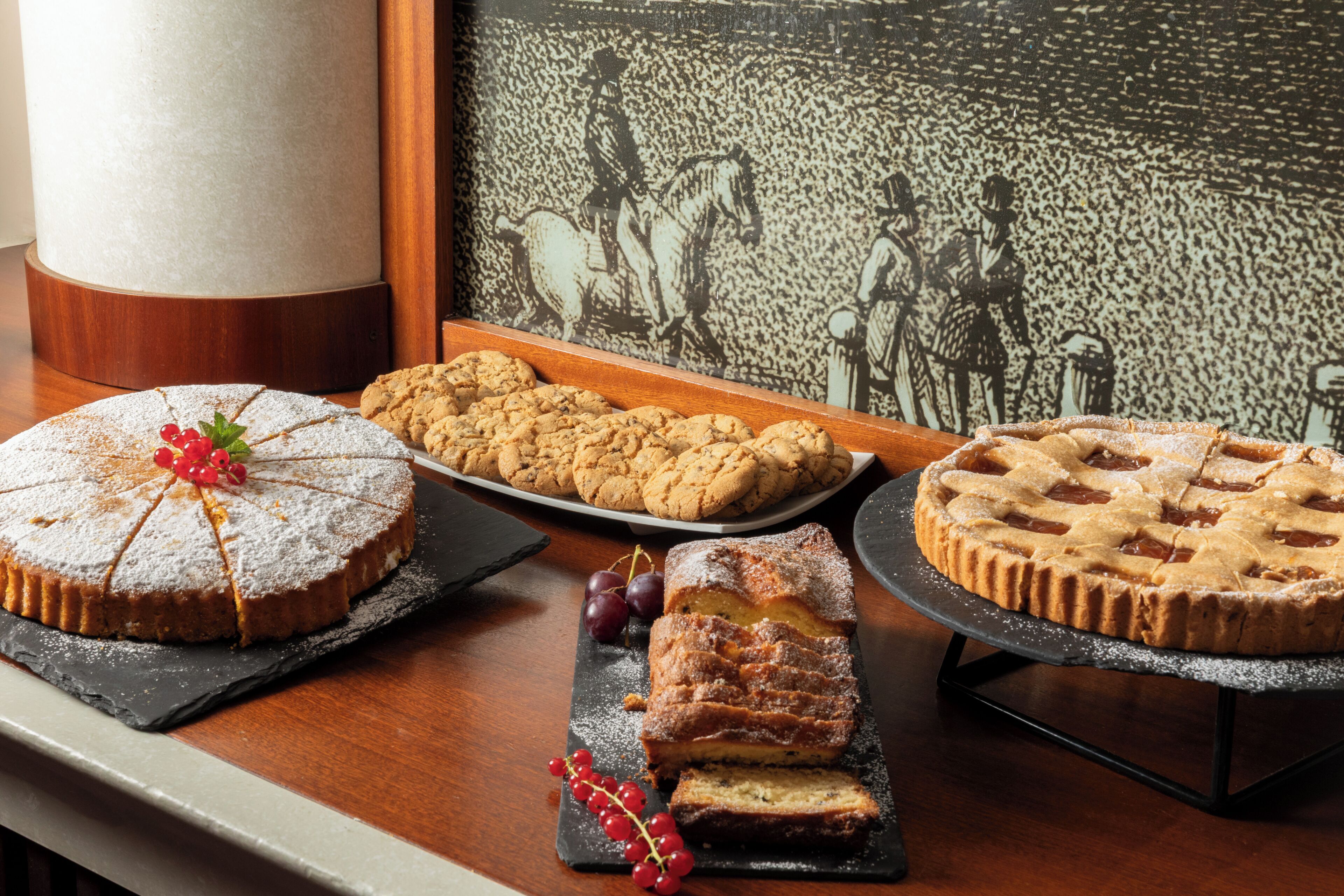 A dessert display with cakes and cookies on a wooden table.