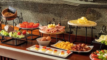 Un buffet de petit-déjeuner proposant une variété d’aliments, notamment des œufs, du bacon et des légumes.