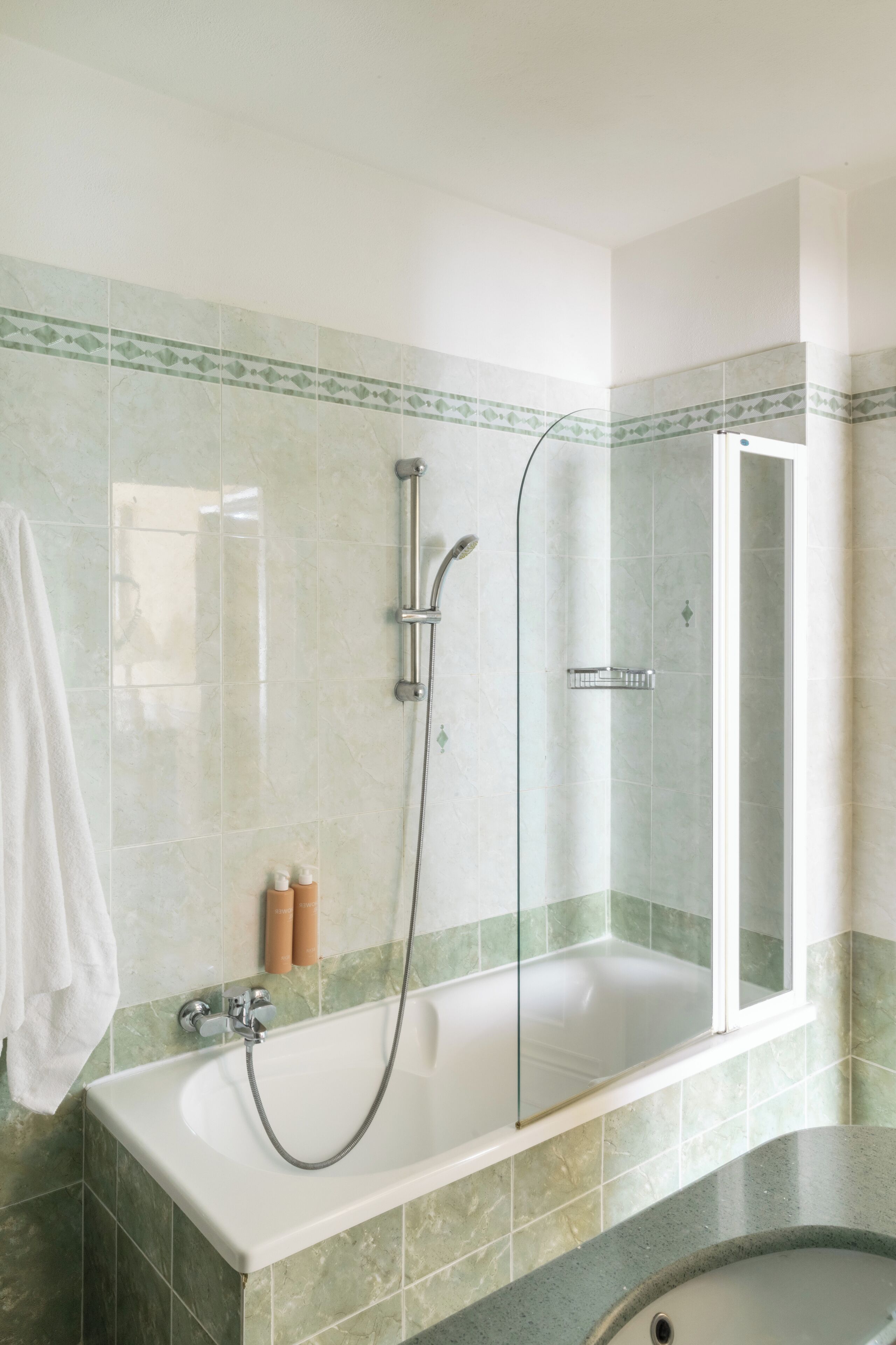 A bathroom with a bathtub, shower, and glass-enclosed shower stall.