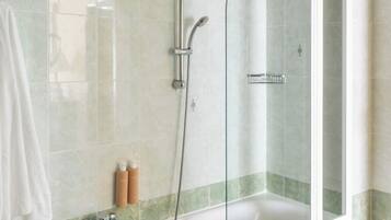 Un baño con bañera, ducha y cabina de ducha con paredes de vidrio.