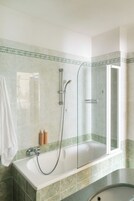 Un baño con bañera, ducha y cabina de ducha con paredes de vidrio.