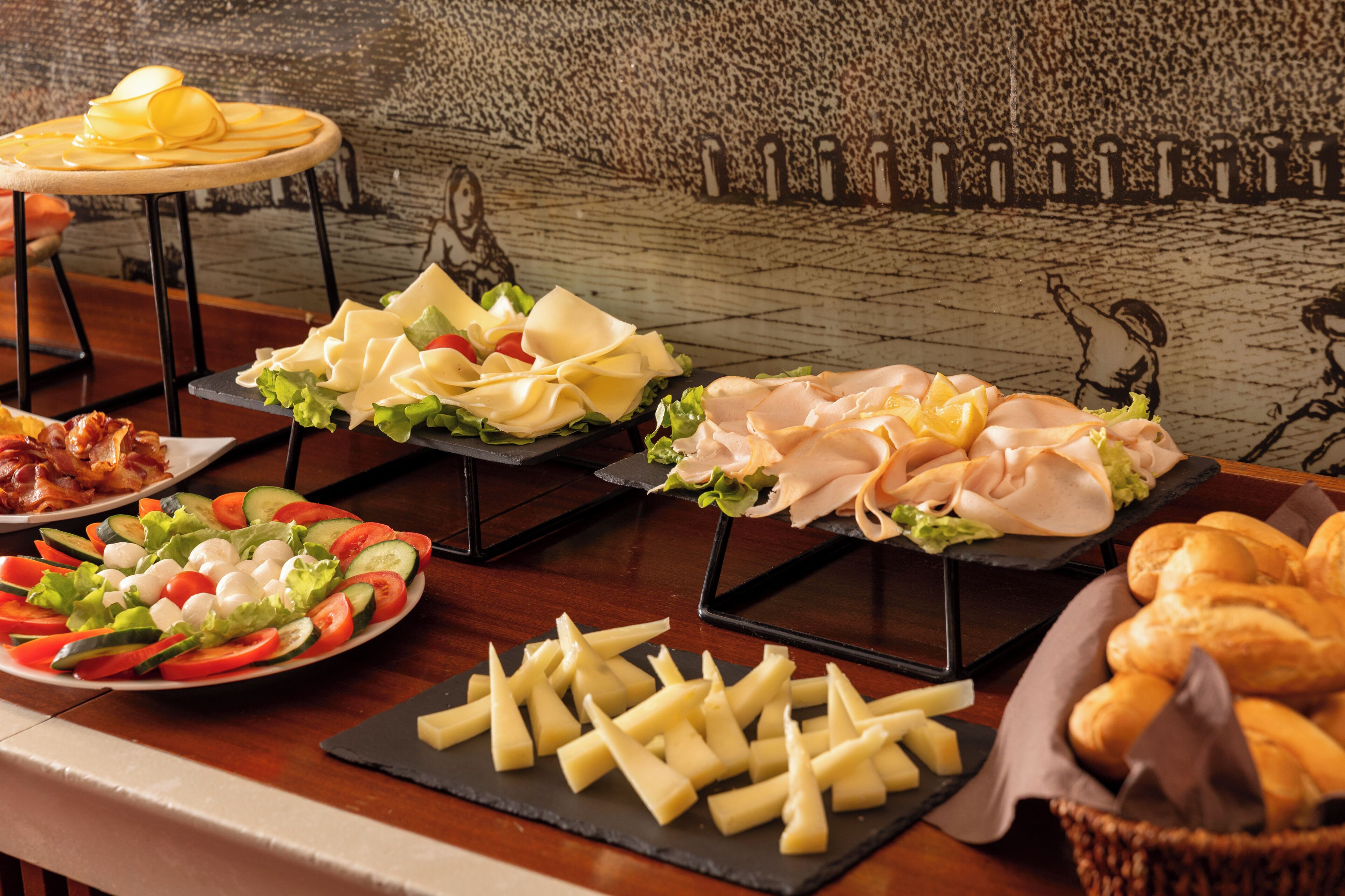 A buffet table with various food items including salads, cheeses, and meats.