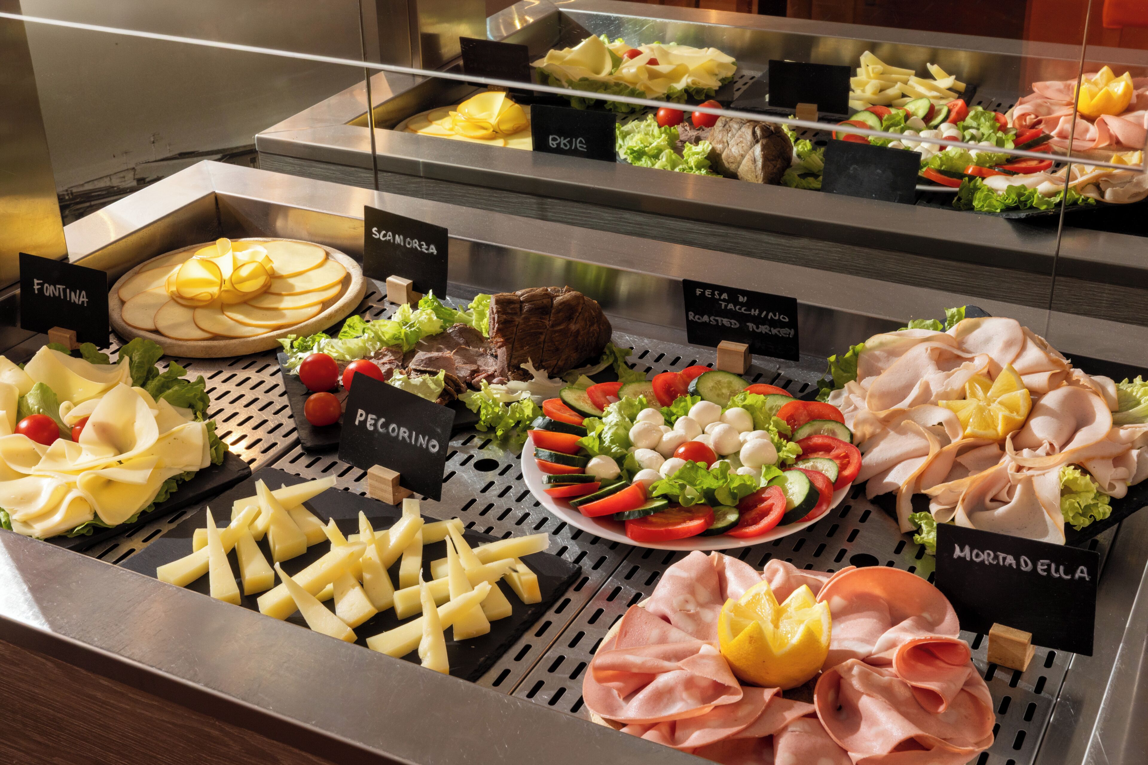 Un bufé con diversas opciones de comida, incluyendo queso, carnes y ensaladas.
