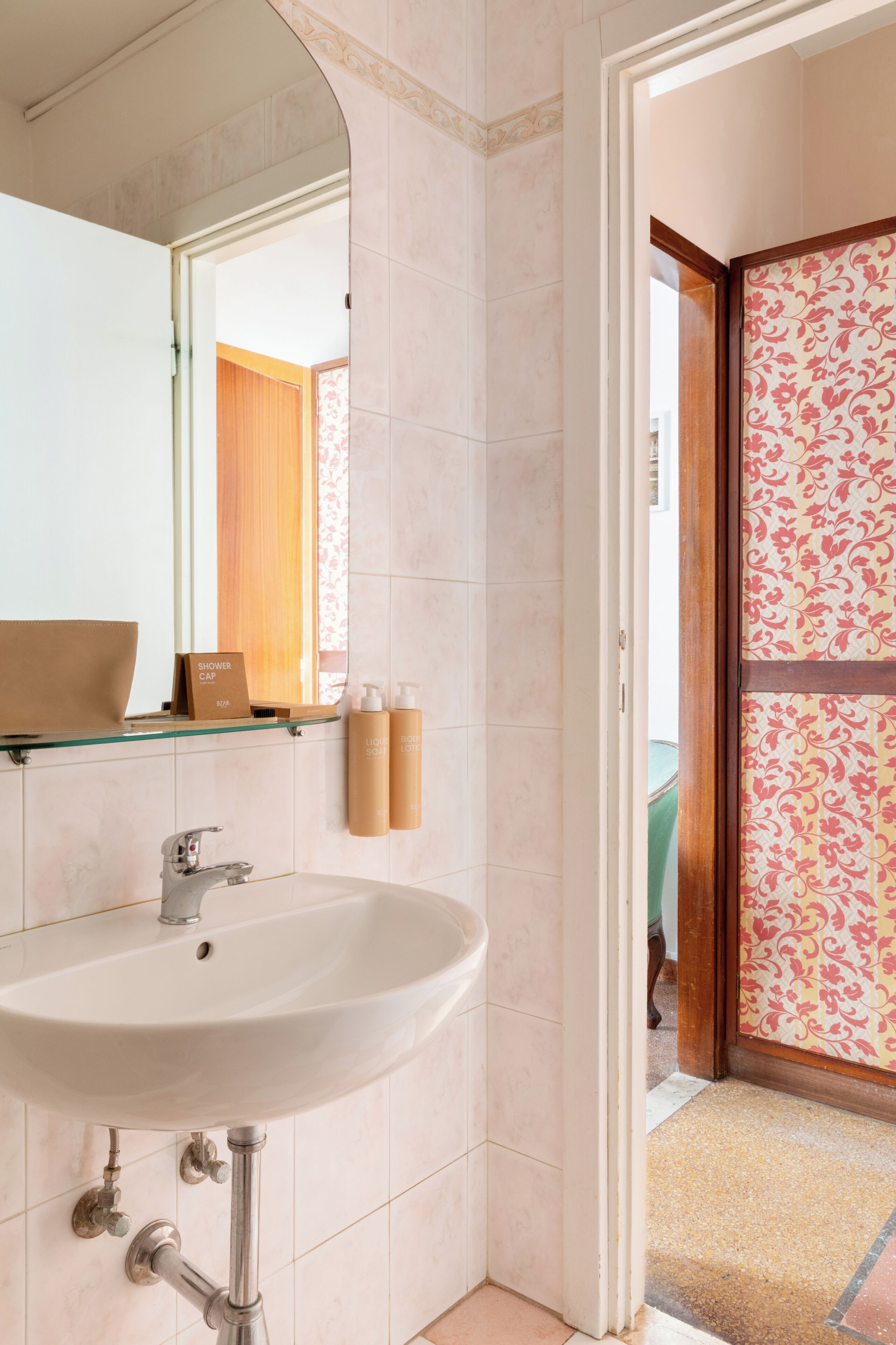 A bathroom with a glass shelf, a white sink, and a shower cap on the wall.