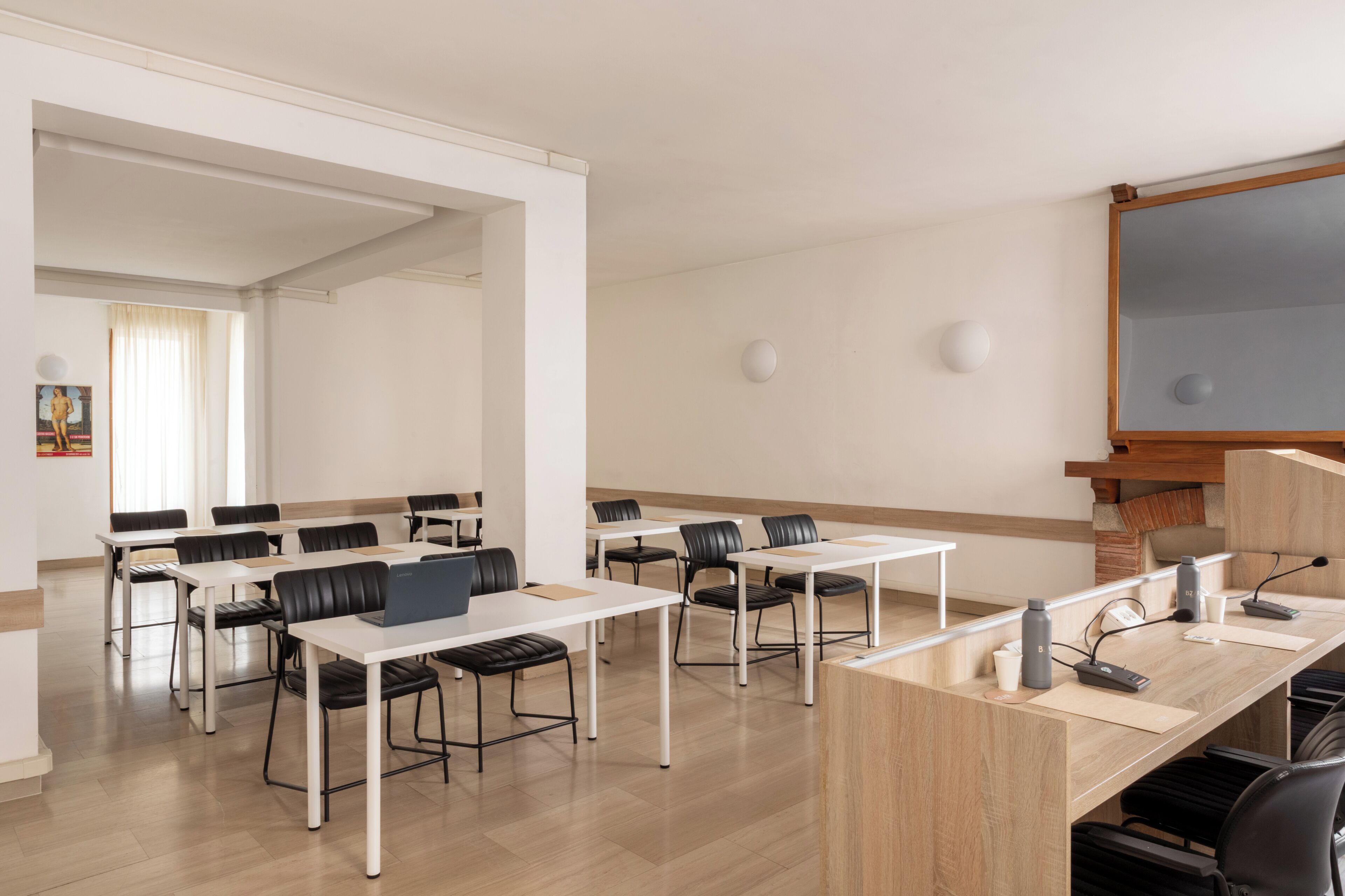 A conference room with white tables, black chairs, a wooden podium, and a whiteboard.