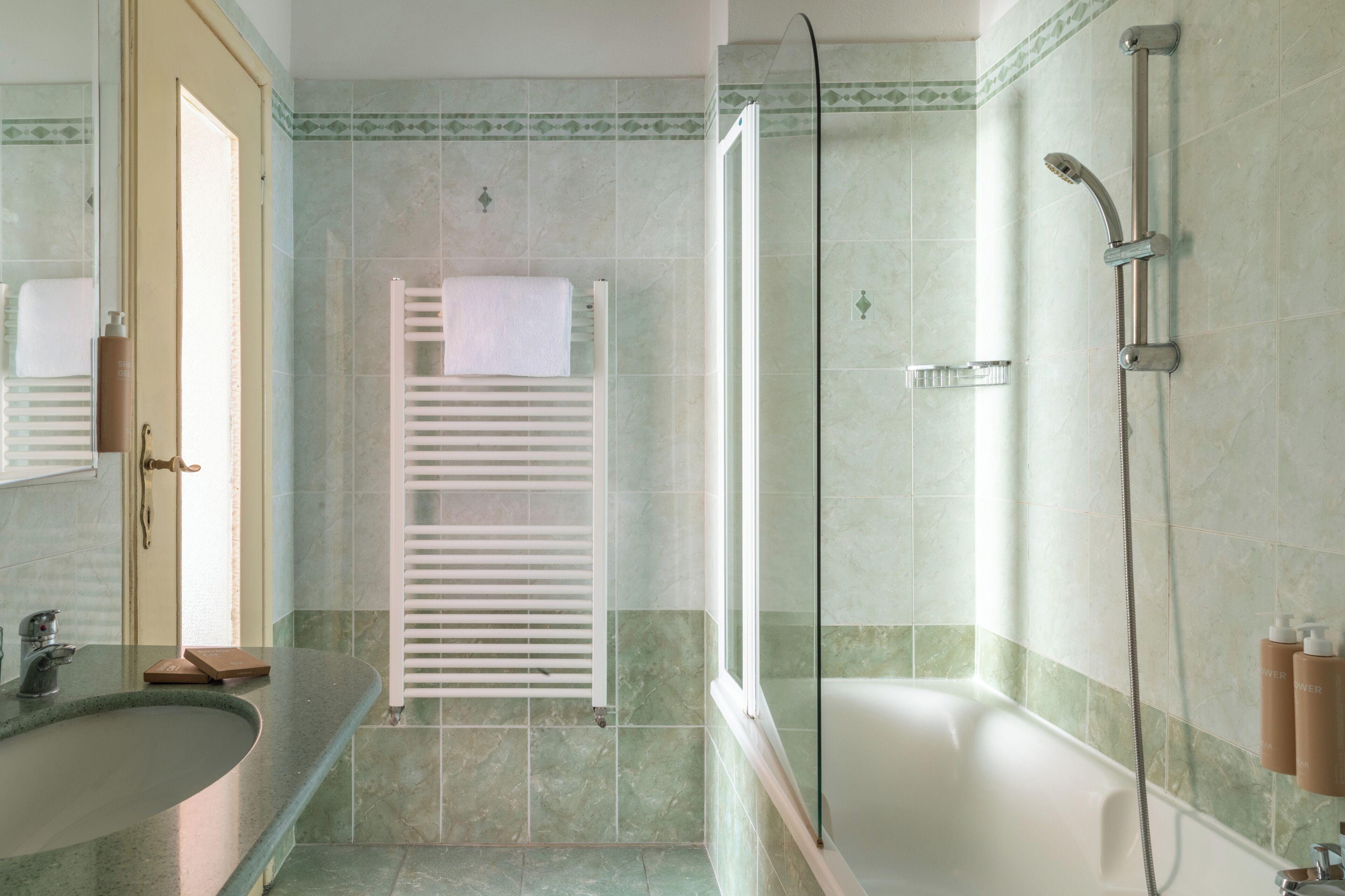 A bathroom with a bathtub, a glass-enclosed shower, a towel rack, and a sink.