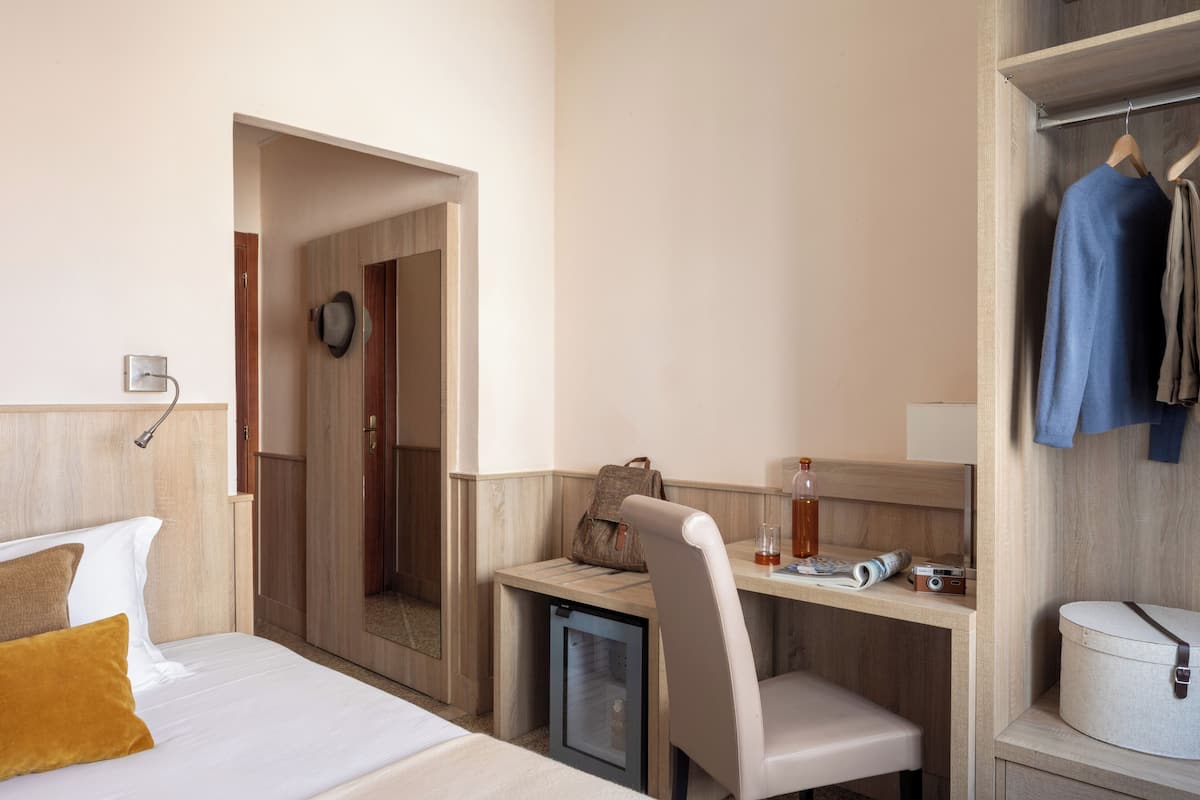 Ein Hotelzimmer mit Bett, Schreibtisch, Stuhl und einem Kleiderschrank mit Kleidung.