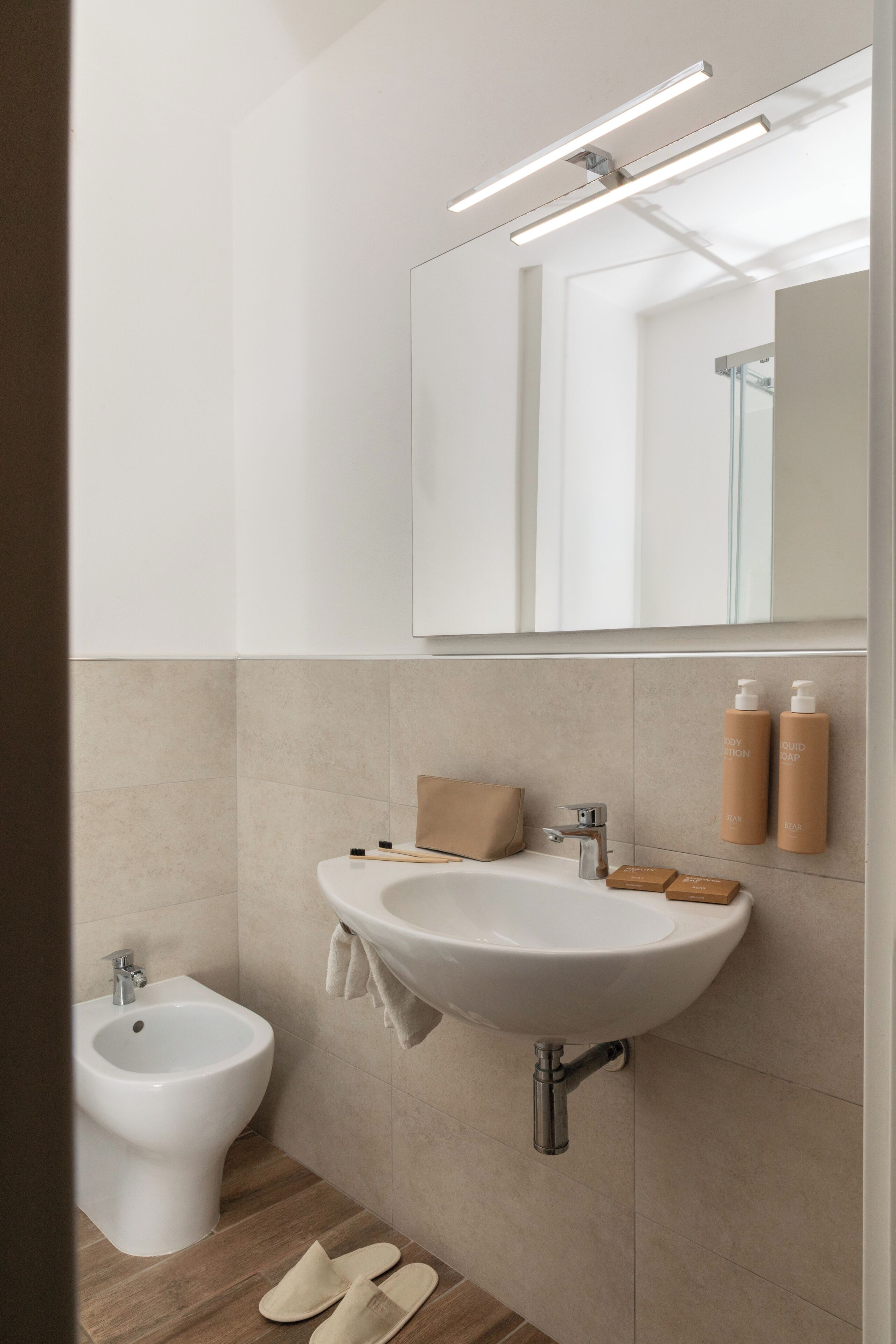 Une salle de bain moderne avec un lavabo blanc, un bidet et un miroir.