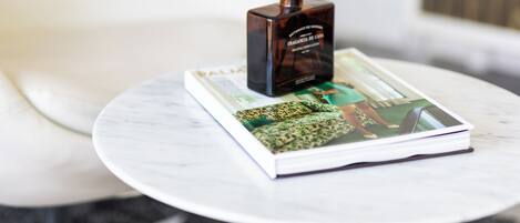 Una mesa blanca con una revista y un difusor de caña.
