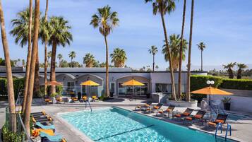 Una piscina al aire libre, sombrillas, sillones reclinables de piscina