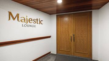 A hallway with a sign reading "Majestic Lounge" on the wall, wooden doors, and a wooden handrail.