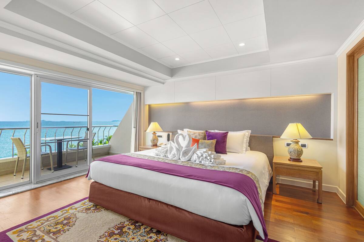 A spacious bedroom with a large bed, a balcony with a view of the sea, and a modern design.