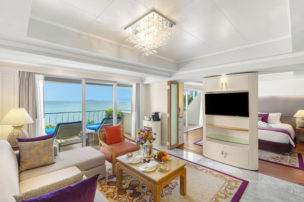 A hotel room with a balcony, a TV, a bed, and a dining area.