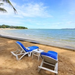 Relax on the beach with two lounge chairs and a small table, overlooking the ocean.