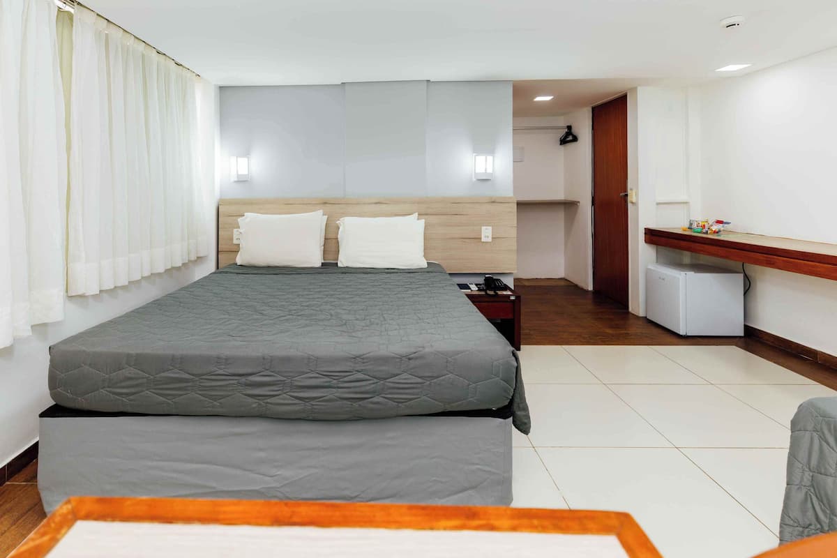 Habitación de hotel con cama, escritorio, silla y una pequeña kitchenette.