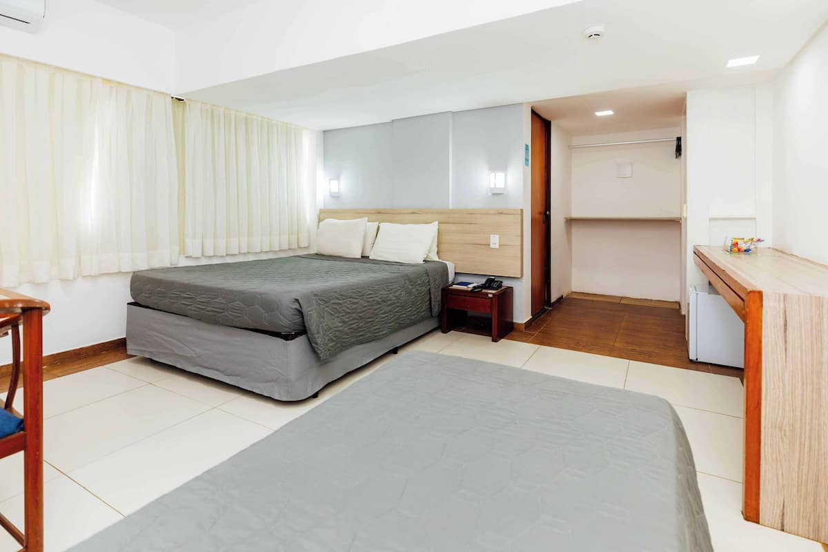 Una habitación de hotel con cama, mesita de noche y zona de escritorio.