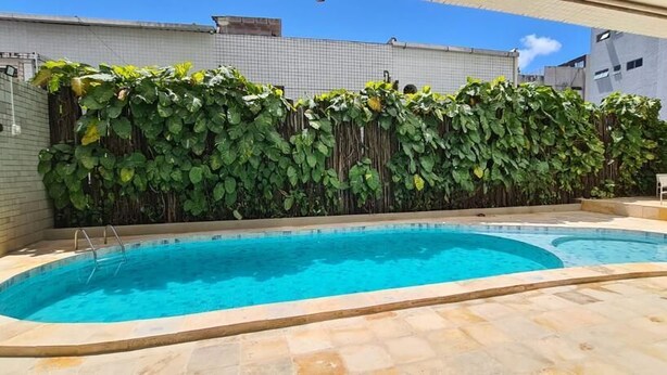A swimming pool with a tiled deck, surrounded by a lush green hedge. - EL ARAM BEACH BOA VIAGEM (Recife)