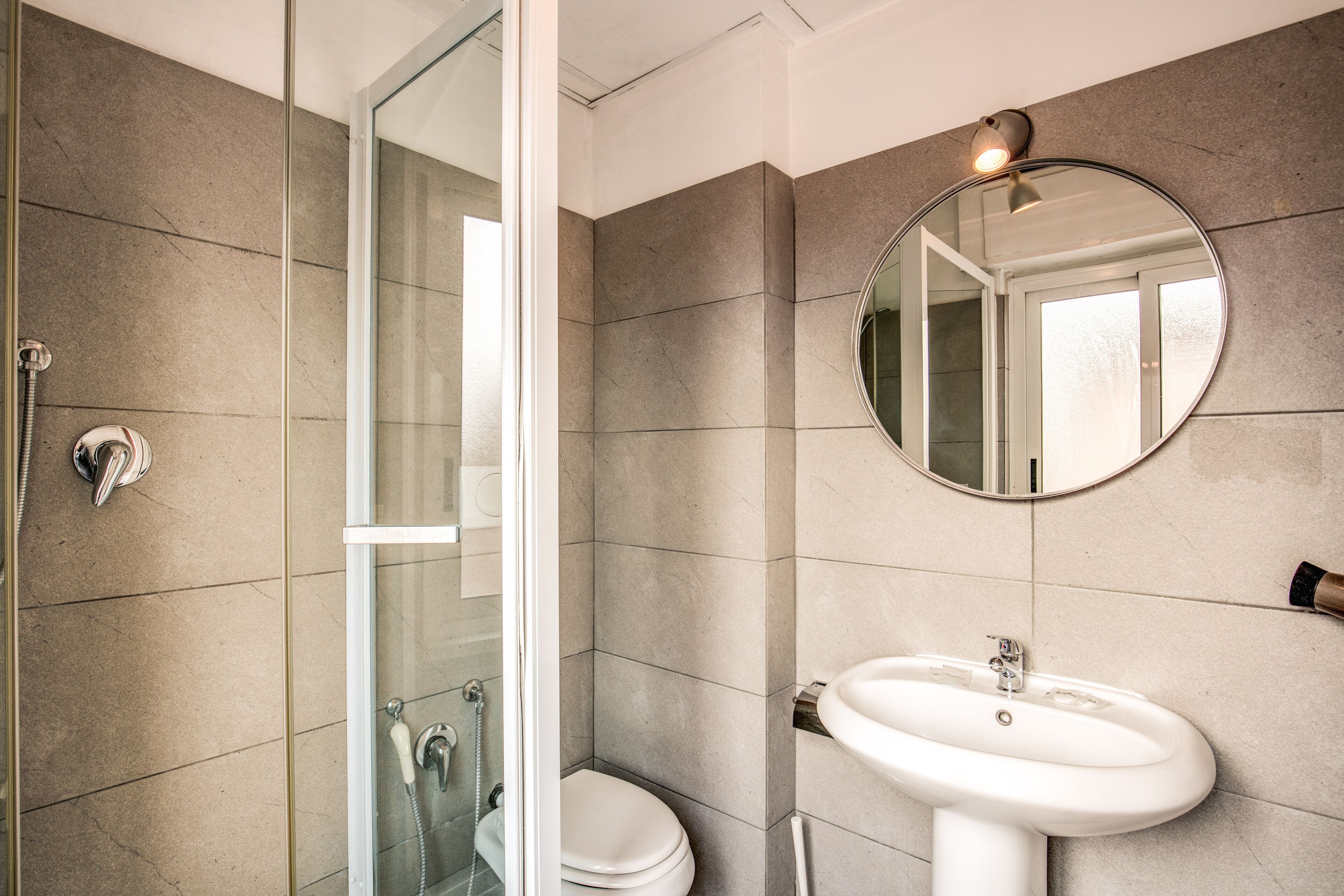 A bathroom with a glass-enclosed shower, a white toilet, and a pedestal sink.